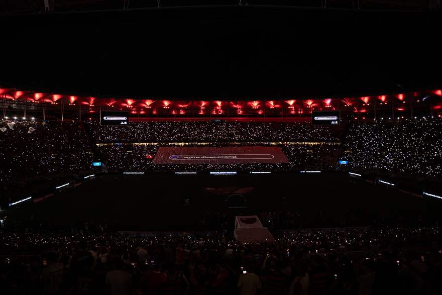 Barra de prompt da Meta AI projetada no bandeirão, digitada ao vivo diante da torcida