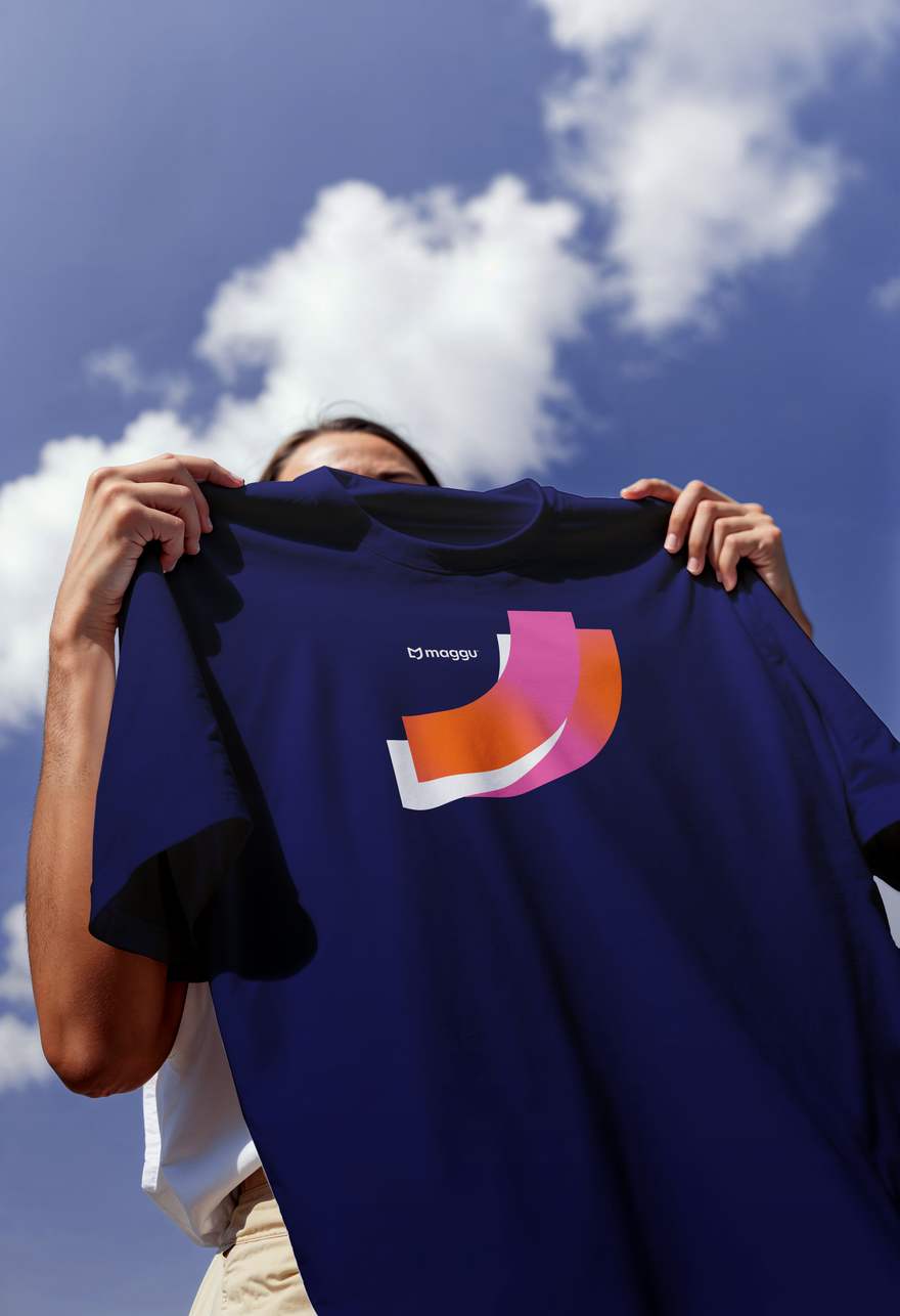 Camiseta azul com o grafismo em degradê rosa e laranja contra o céu